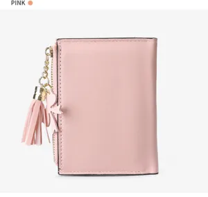 Pink short wallet detail shot showing the zipper, tassel charm, and compact design.