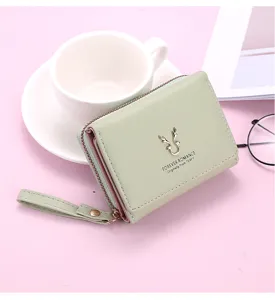 Vue détaillée du portefeuille court en cuir PU vert pâle avec design à trois volets et logo cerf.
