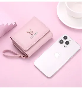 Gros plan sur le portefeuille rose court avec logo cerf, design trifold compact et lanière.