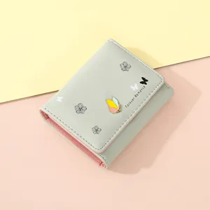 Close-up detail of the light green short women wallet with cute butterfly charm and floral print.