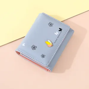 Close-up detail of short women trifold wallet in light blue with cute butterfly design.