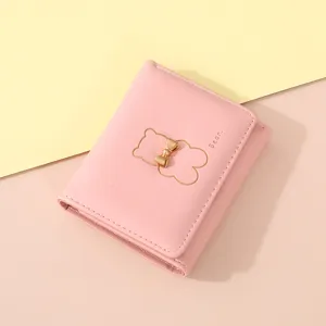 Detailopname van roze lederen portefeuille met schattig beren- en strikdetail.