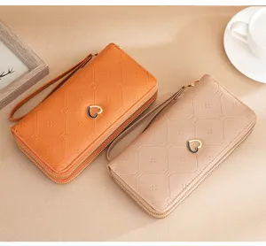 Detailed view of women's long double zipper wallet with heart charm and wrist strap chic design.