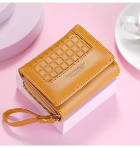 Close-up view of the yellow short wallet featuring a wrist strap, grid embossed flap and card slots.