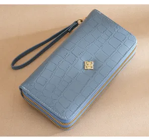 Close-up view of a stylish blue double-layer wallet clutch with elegant crocodile pattern.