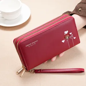Detalles de cartera roja larga con cremallera doble, correa de muñeca y estampado.
