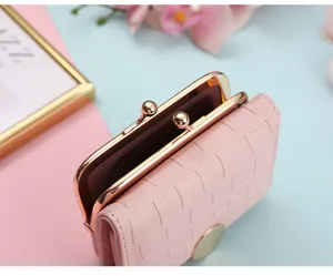 Close-up detail of pink leather short wallet with metal kiss-lock clasp and stylish texture.