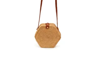 Hexagonal woven rattan straw shoulder bag with brown leather strap detail close up view.