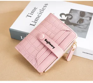 Close-up of a pink bifold short wallet with crocodile texture and card slots detail.