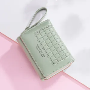 Detailed view of light green short women wallet with wrist strap and grid embossed flap.