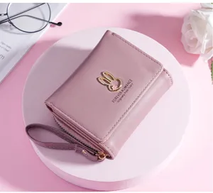 Roze korte damesportemonnee gedetailleerd overzicht met schattig metalen konijnenlogo en polsbandje.