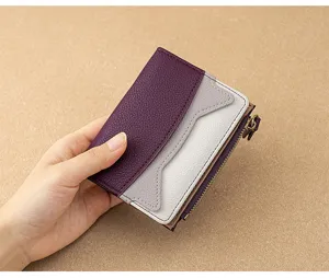 Close-up detail of a compact two-tone leather wallet with zipper pocket and card slots.