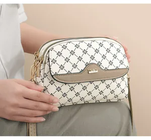 Close-up detail of chic monogram crossbody bag with multi-zipper compartments and flap.