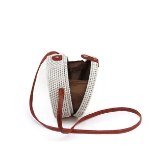 White round rattan straw crossbody bag with brown leather strap, stylish woven summer beach shoulder bag.