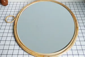 Dettaglio specchio decorativo rotondo in rattan, cornice intrecciata con pratico gancio.