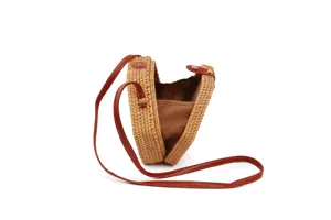 Round rattan crossbody bag detail showing brown leather strap and fabric inner lining.