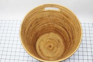 Detailed view of the round woven rattan laundry hamper, showcasing the natural texture and handles.