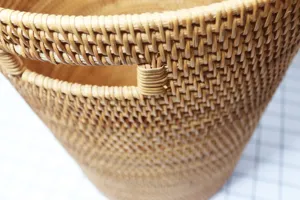 Handwoven rattan storage basket laundry hamper with built-in handles for home organization.