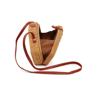 Round straw woven crossbody bag with brown leather strap for women summer beach travel.