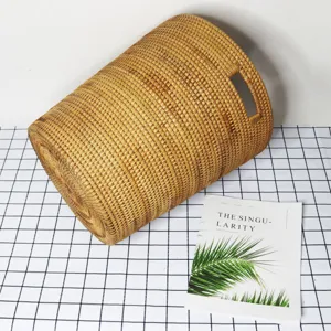 Handwoven rattan laundry basket cylindrical storage hamper with side handles for organization.