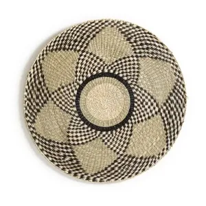 Handcrafted round straw woven wall hanging detail with unique black geometric pattern decor.