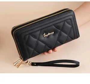 Detail view of black quilted long wallet with double zippers, gold metal logo and wrist strap.