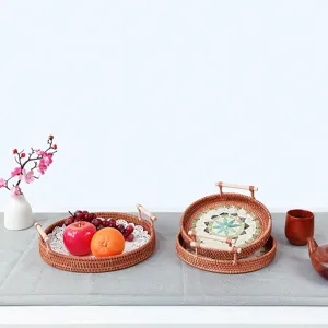 Detail view of woven rattan serving tray with wooden handles and colorful shell mosaic base.