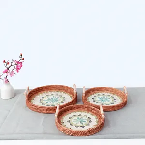 Handmade rattan woven tray with colorful shell mosaic and wooden handles for home decor.