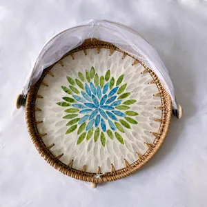 Detail view of handmade rattan fruit basket with colorful seashell mosaic and white net.