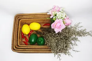 Detailed top view of nested rectangular woven rattan storage baskets with artificial fruit decor.