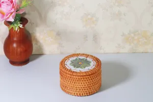 Dettaglio scatola portaoggetti in rattan intrecciato, trama naturale con coperchio in ceramica.