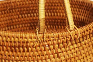 Handwoven rattan storage basket detail, natural wicker fruit container with dual handles.