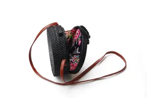 Detailed view of the black round woven rattan crossbody bag featuring a floral inner lining.