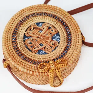 Détail en gros plan d'un sac rond en rotin tissé à la main avec bandoulière en cuir.