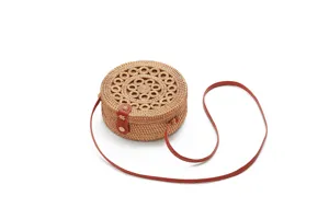 Close-up detail of the round woven rattan crossbody bag, showing intricate straw pattern.