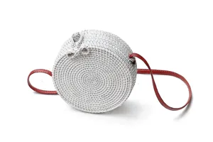 Detailed close-up view of the white woven rattan round crossbody bag featuring a red strap.