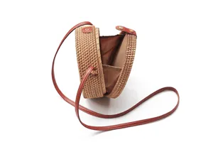 Detail view of round woven rattan crossbody bag, showing brown interior lining and pocket.