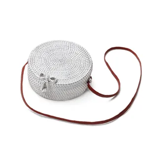White round straw woven cross-body bag for women with brown shoulder strap and bow.