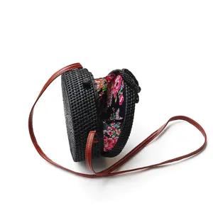 Round black rattan straw crossbody bag with floral lining and brown leather shoulder strap