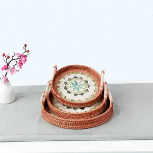 Detailed view of nested round rattan serving trays with wooden handles and mosaic shell inlay.