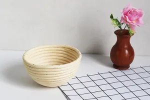 Detailed view of hand-woven round rattan bread proofing basket displayed on table.