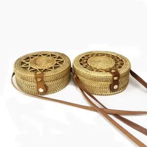 Detail van ronde gewoven rattan crossbody tas, met bruine lederen band en metalen sluiting.
