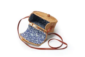 Handcrafted half-round rattan crossbody bag with floral lining and brown leather strap.