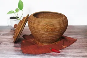 Gros plan détaillé d'un pot de stockage en rotin tissé avec couvercle sur table en bois.