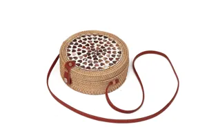 Nahaufnahme einer gewebten Rattan Umhängetasche mit Muschelherz Inlay und Lederriemen.