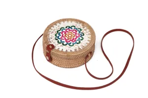 Detaillierte Nahaufnahme der handgefertigten Rattan-Runde Tasche mit bunten Muschelblüten.