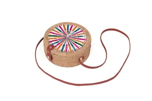 Detailansicht der runden geflochtenen Rattan-Umhängetasche mit buntem Muschel-Mosaik und Lederriemen.