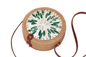 Detailansicht der runden Rattantasche mit grün-weißem Muschel-Inlay im Blumenmuster.