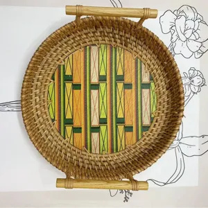 Runde Rattan Serviertablett mit Holzgriffen und farbigem geometrischen Muster Bodeneinsatz.