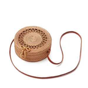 Round rattan shoulder bag with brown leather strap and cute bow, ideal for beach and summer.